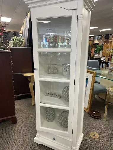 A white cabinet with glass doors and shelves in a store.
