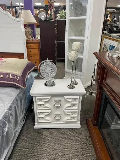 A white nightstand is sitting in a room next to a bed.