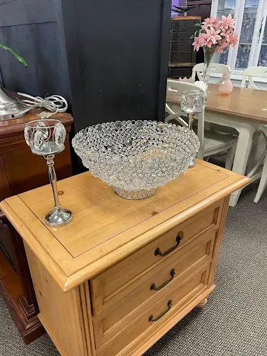 A wooden dresser with a glass bowl on top of it.
