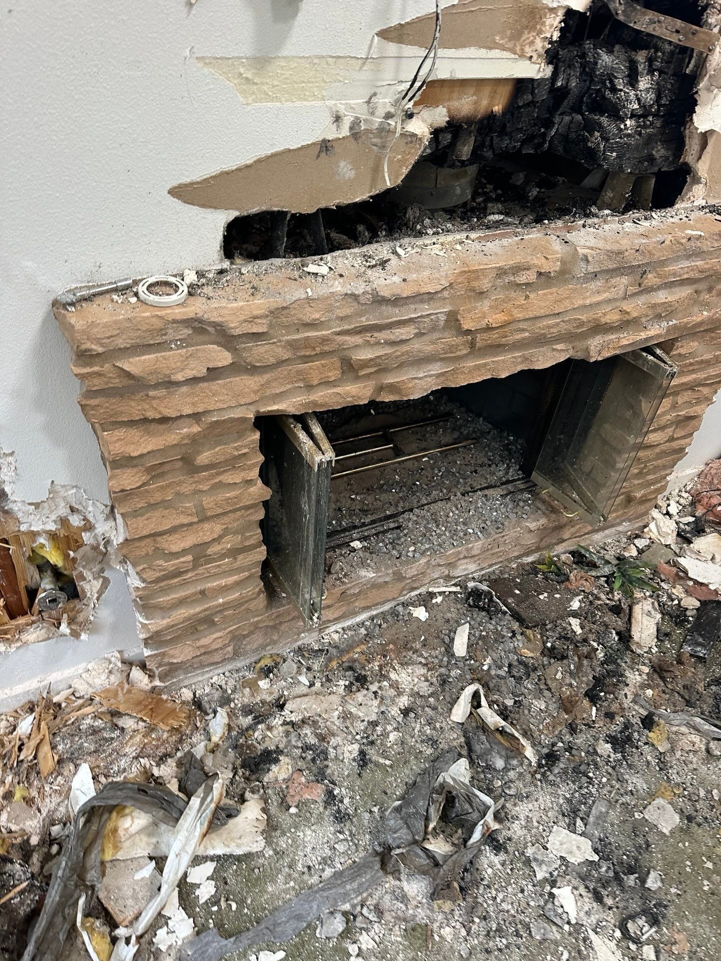 A brick fireplace is being demolished in a house.