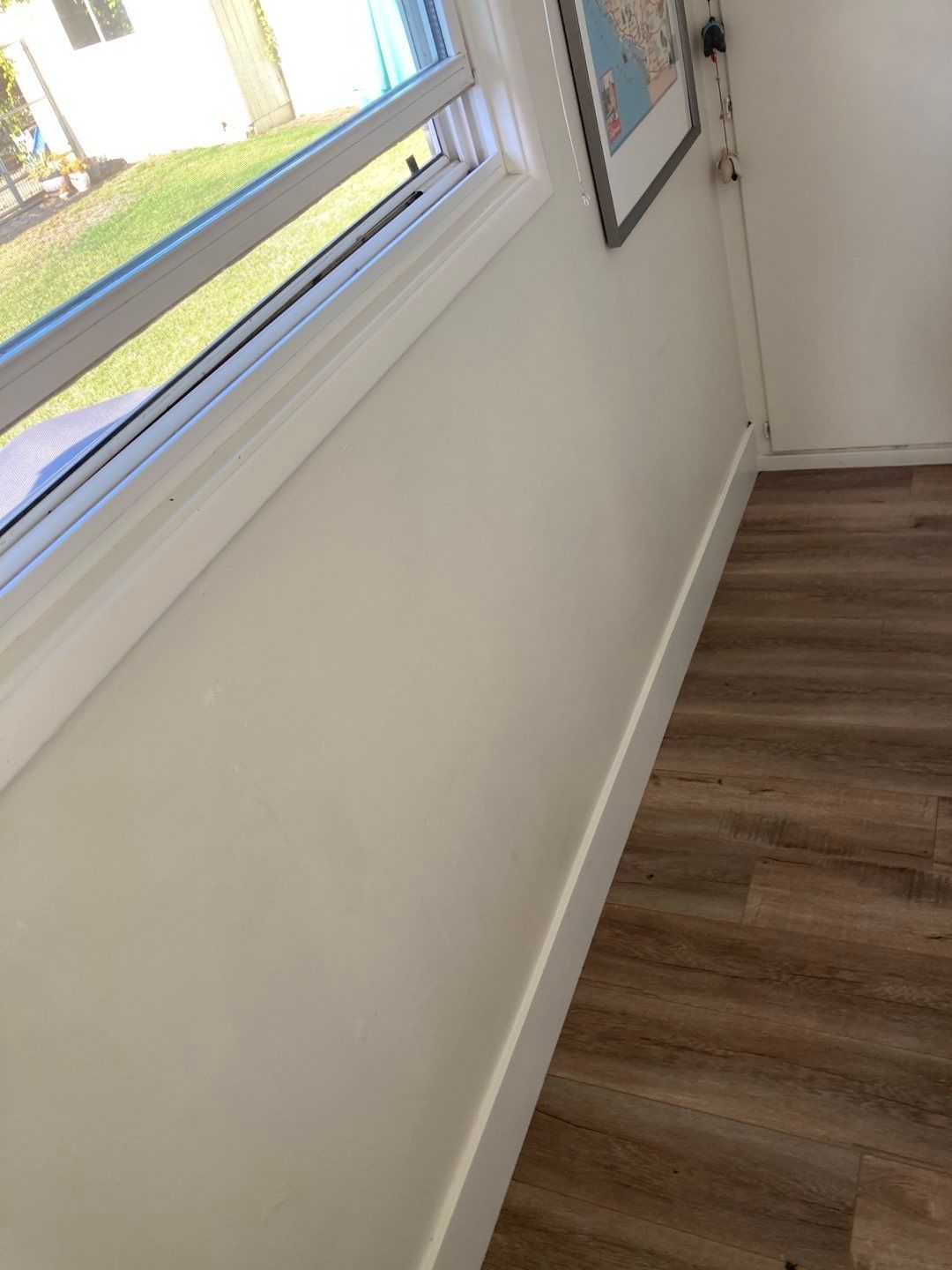 A white wall with a window and a wooden floor in a room.