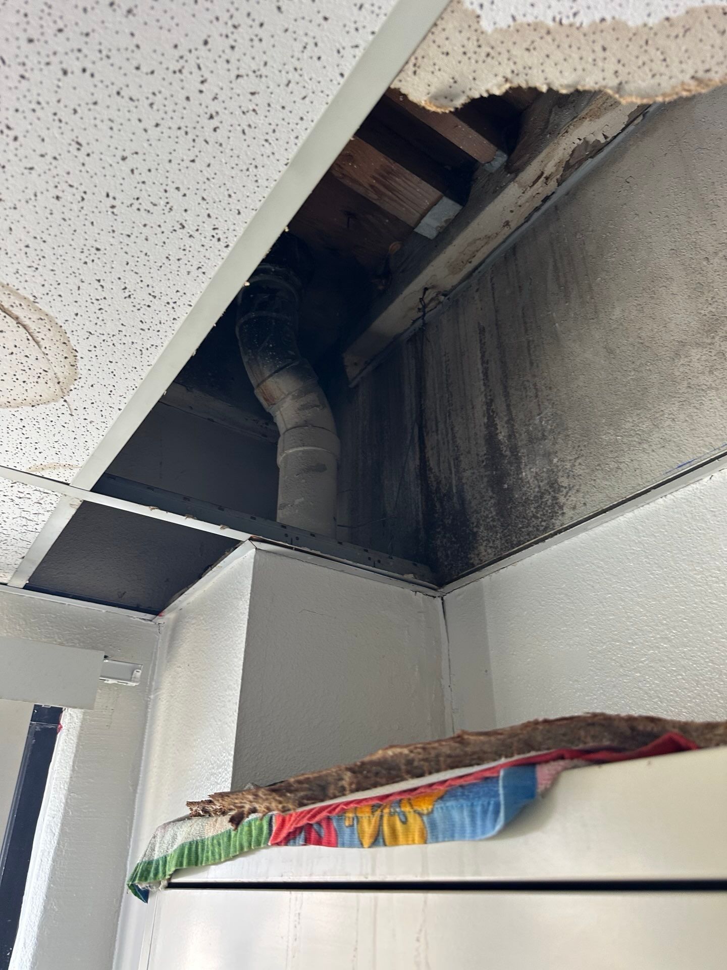 A ceiling with a hole in it and a pipe coming out of it.