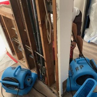 A man is working on a wall next to a blue dryer in Huntington Beach.