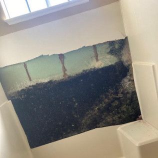 A bathroom with a hole in the wall and a window in Huntington Beach.