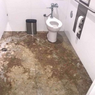 A toilet in a bathroom with a dirty floor in Irvine.