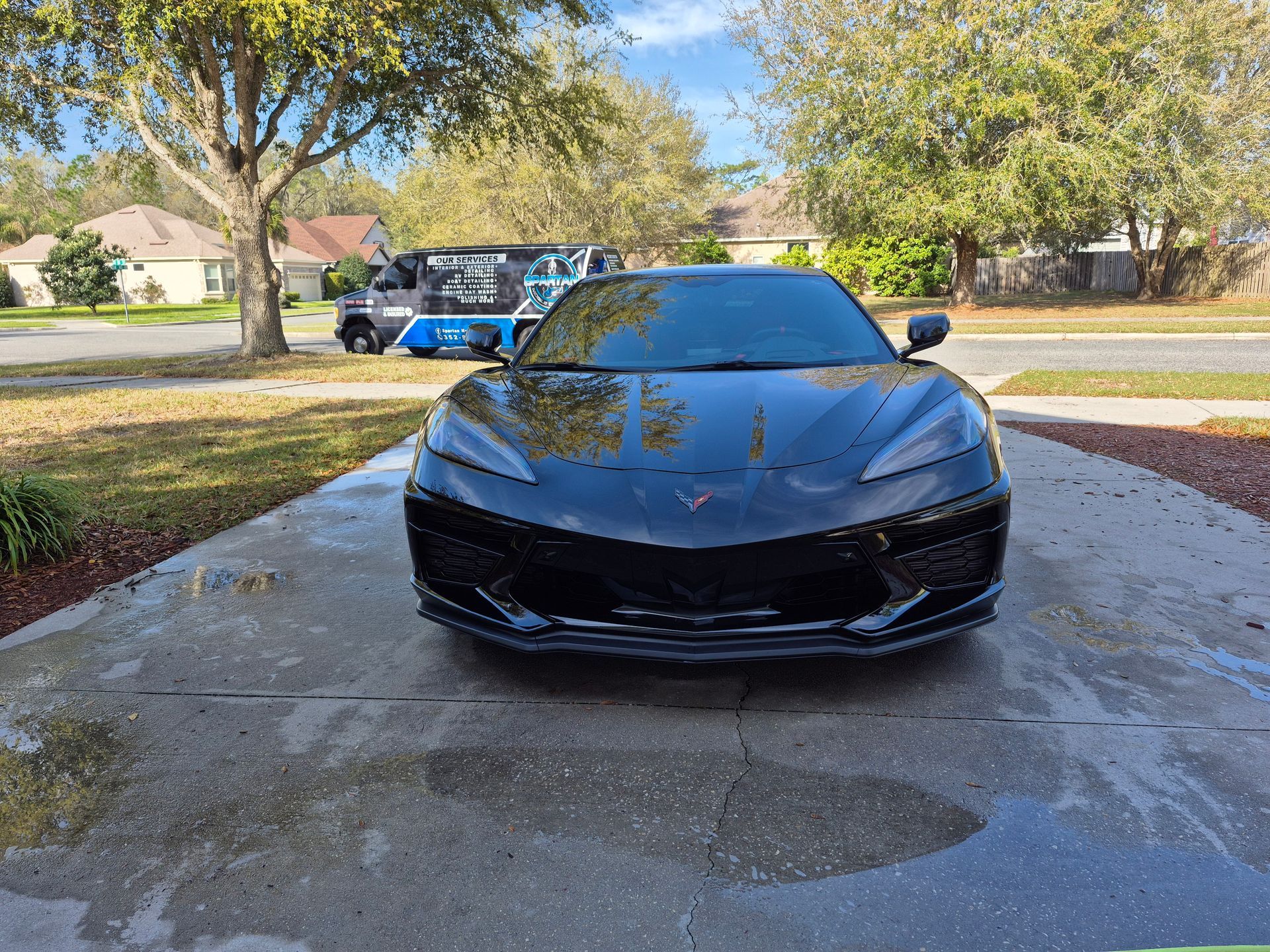 A black sports car is parked in a driveway next to a golf cart.