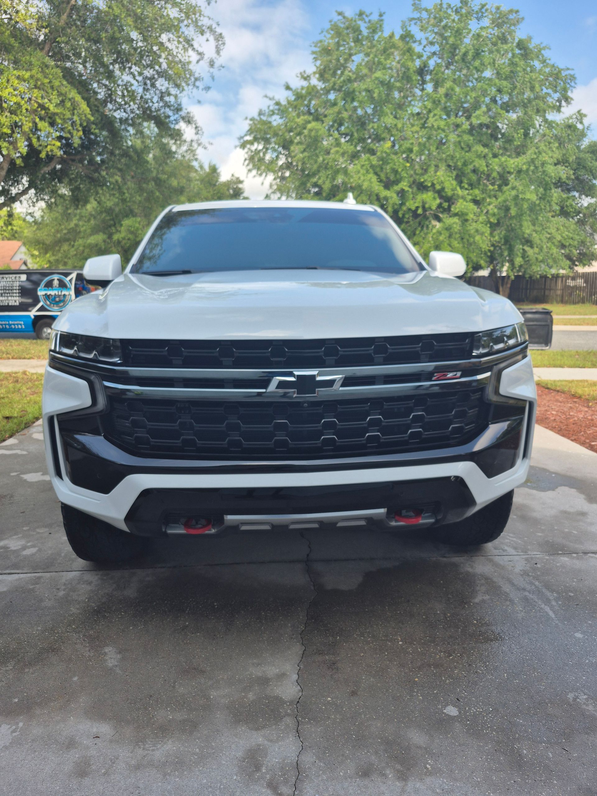 A white chevrolet truck is parked in a driveway.