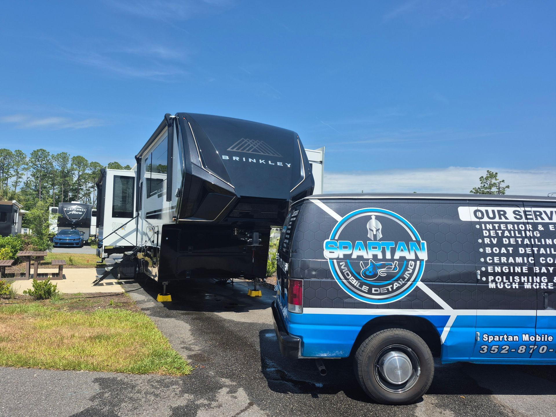 A van is parked next to a rv in a parking lot.