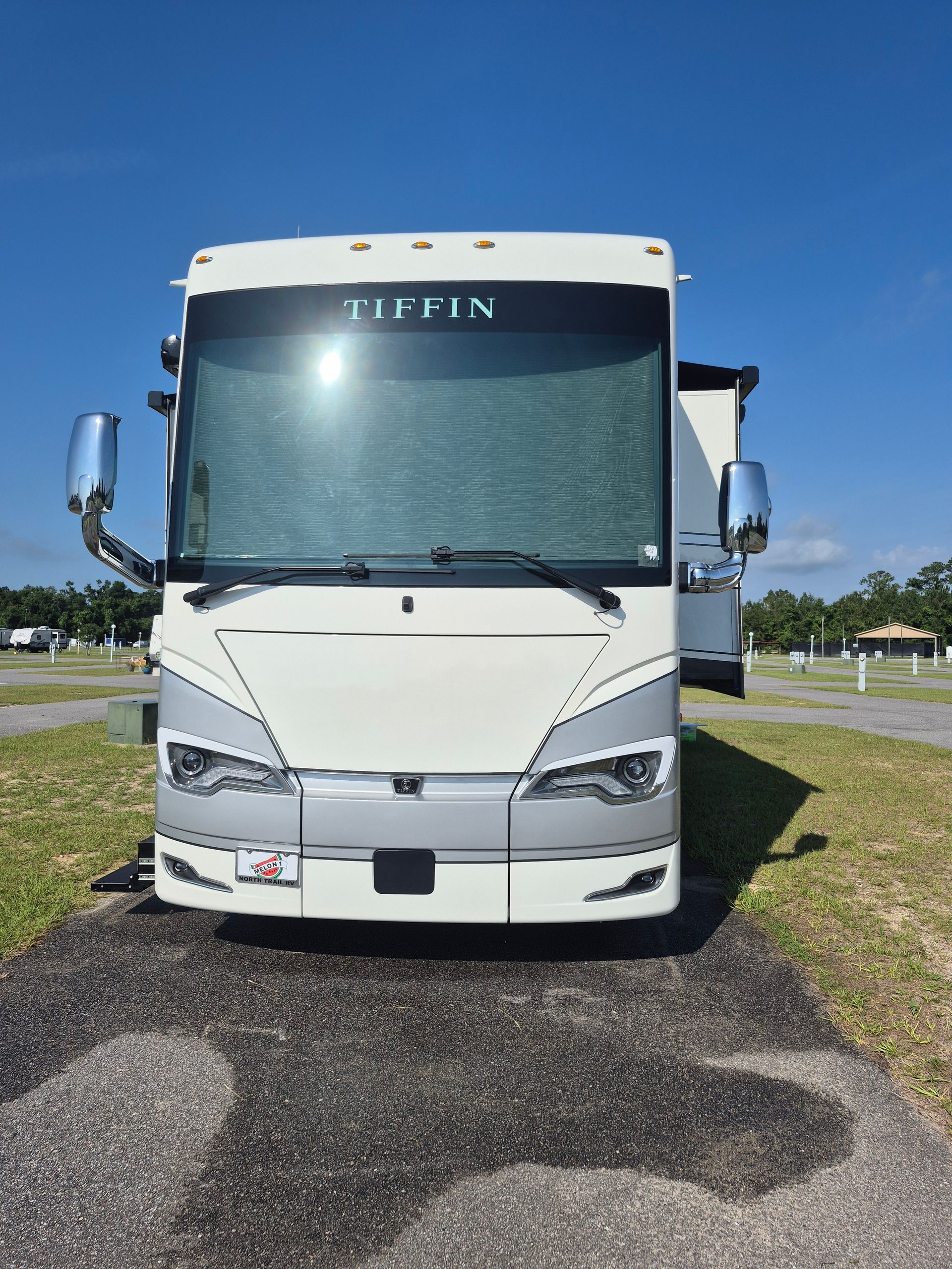 A white rv is parked in a grassy area.