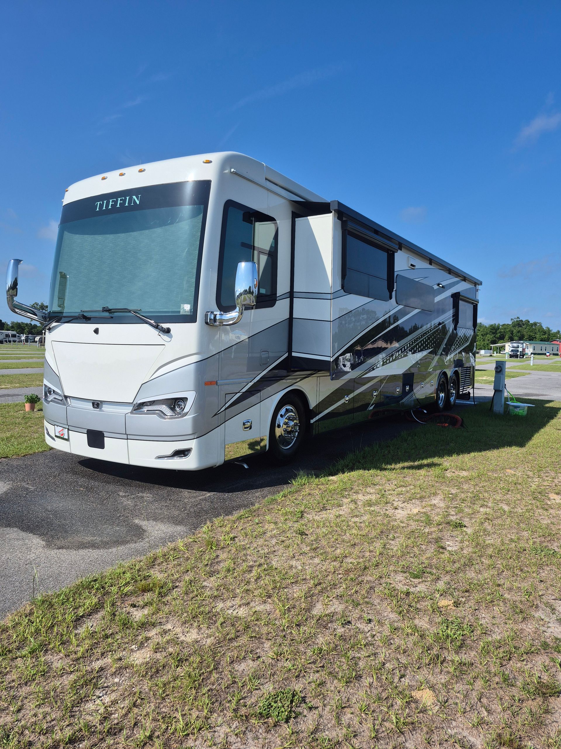 A large white rv is parked in a grassy field.