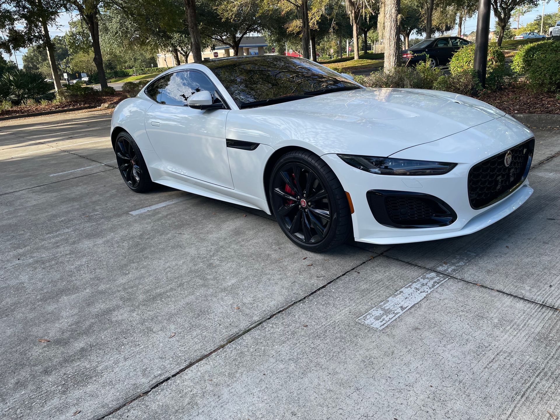 A white sports car is parked on the side of the road.