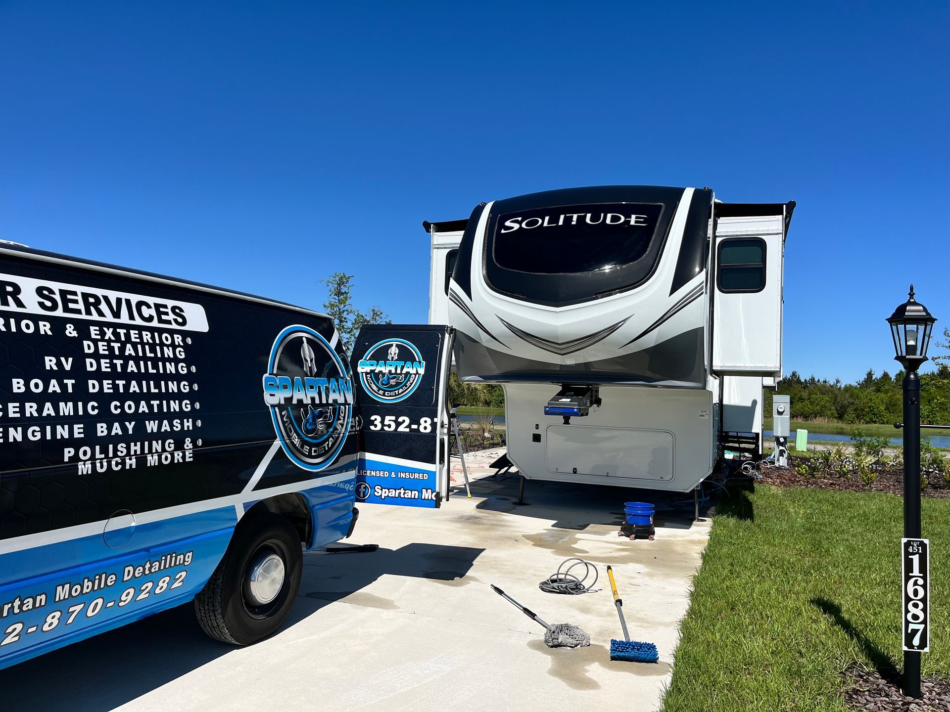 A rv is parked in a driveway next to a truck.