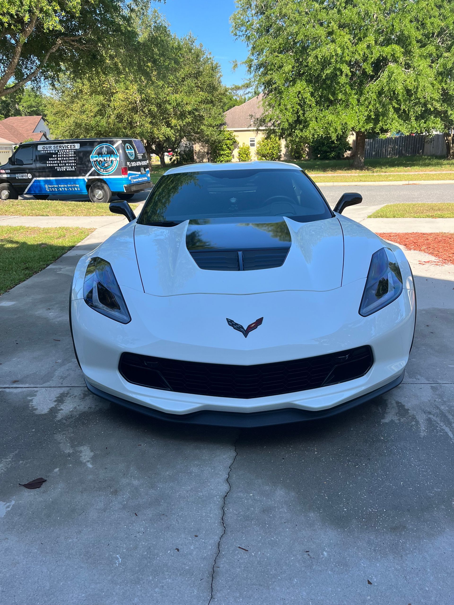A white sports car is parked in a driveway.