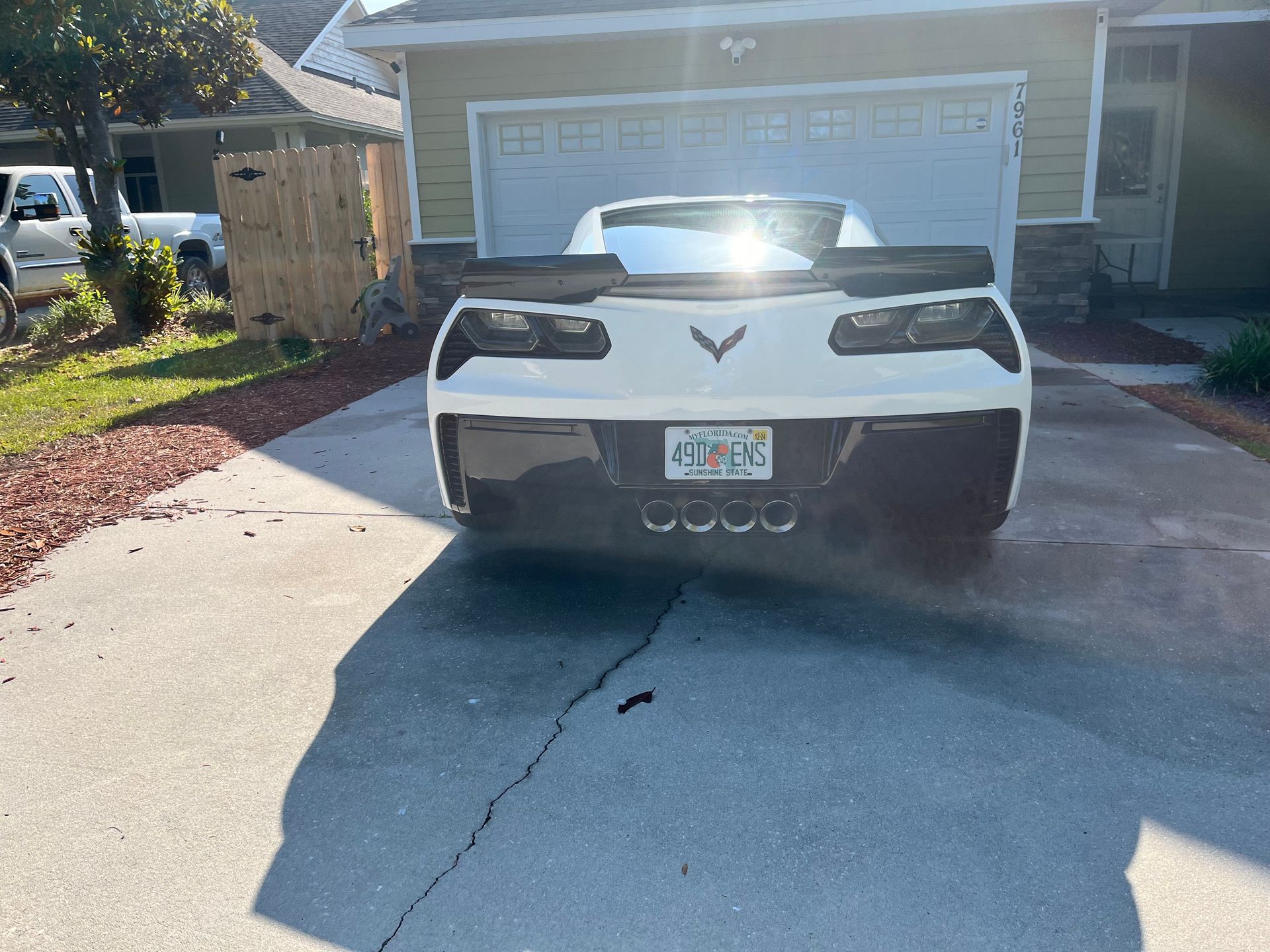 A white corvette is parked in a driveway in front of a house.