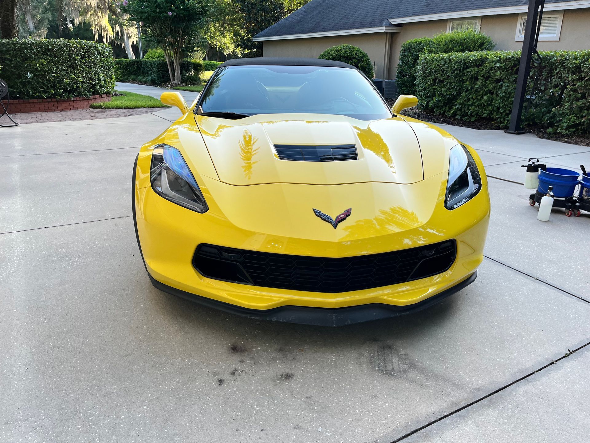 A yellow sports car is parked in a driveway in front of a house