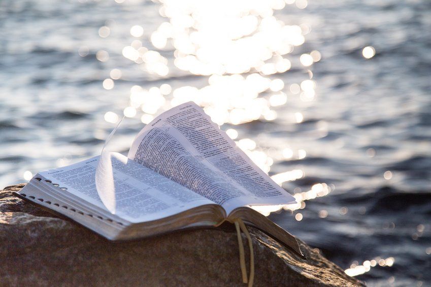 Bible open. Light reflected on water.
