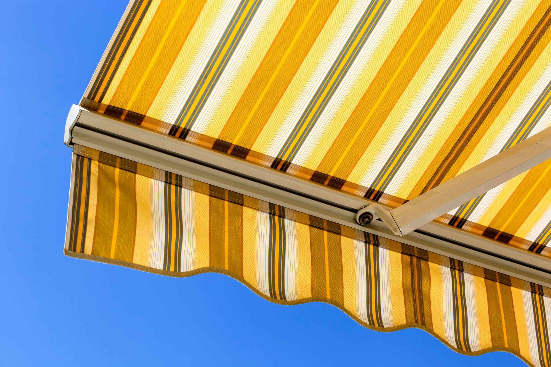 Tenda a strisce gialle e bianche contro un cielo azzurro terso.