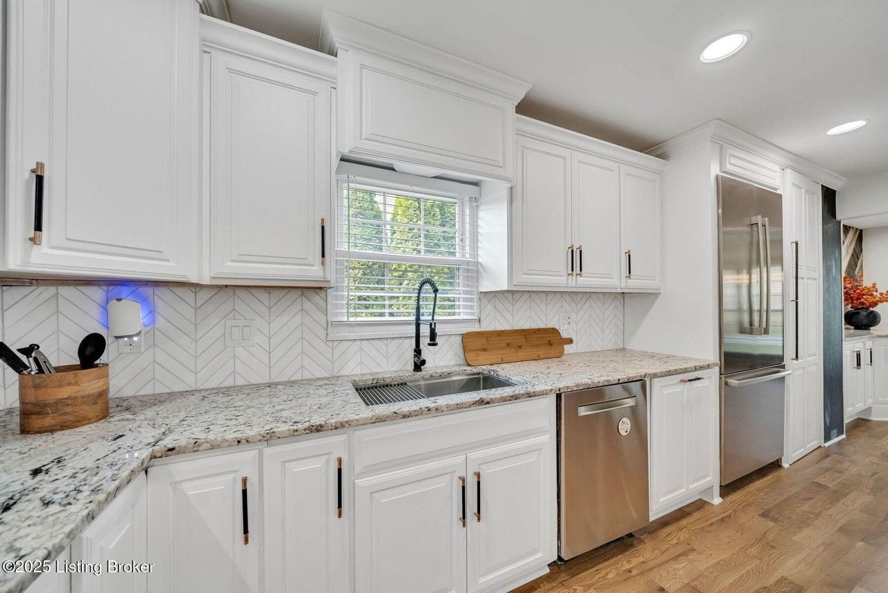 White kitchen with granite countertops, stainless steel appliances, and window above the sink.