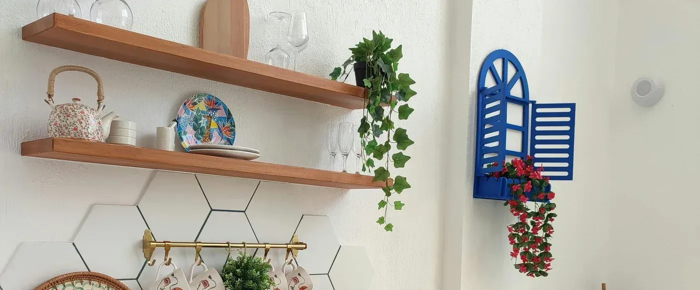 Kitchen scene with shelves, teapot, and blue window decor with hanging plants.