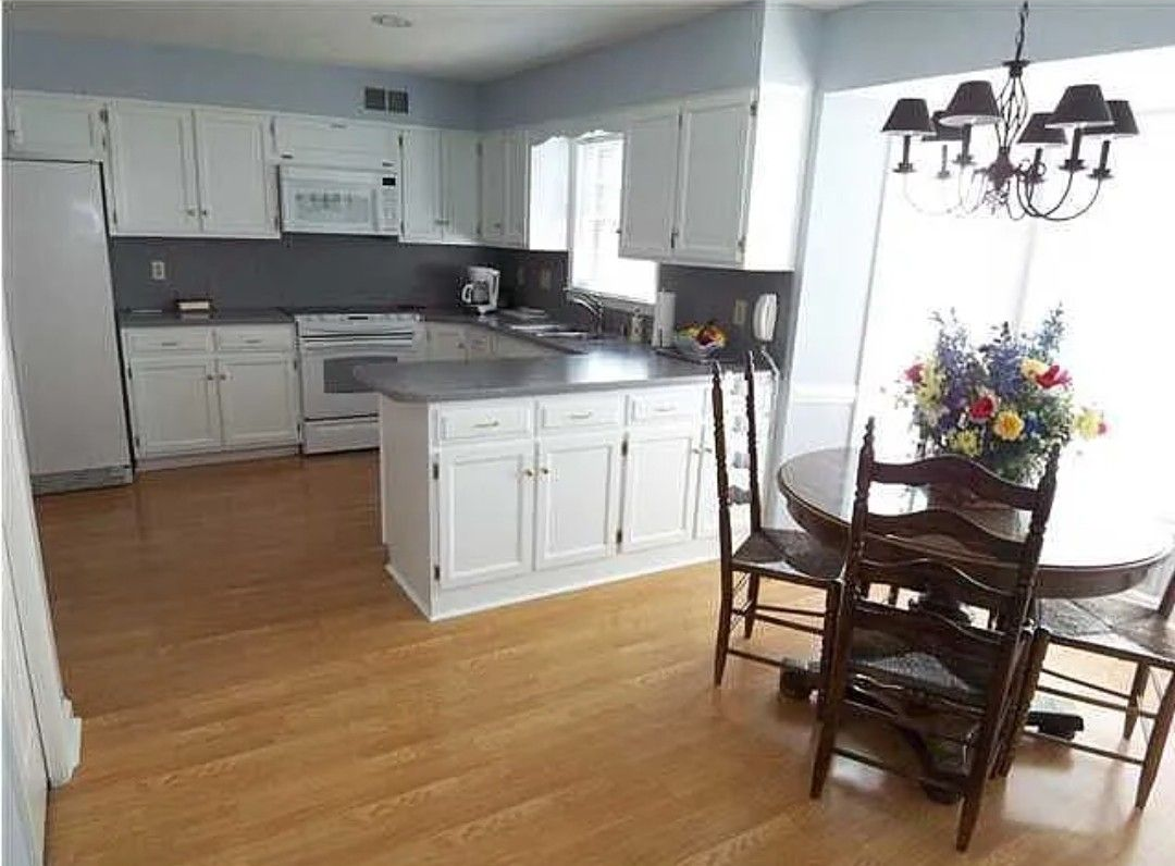 Kitchen with white cabinets, gray countertops, and a dining table.