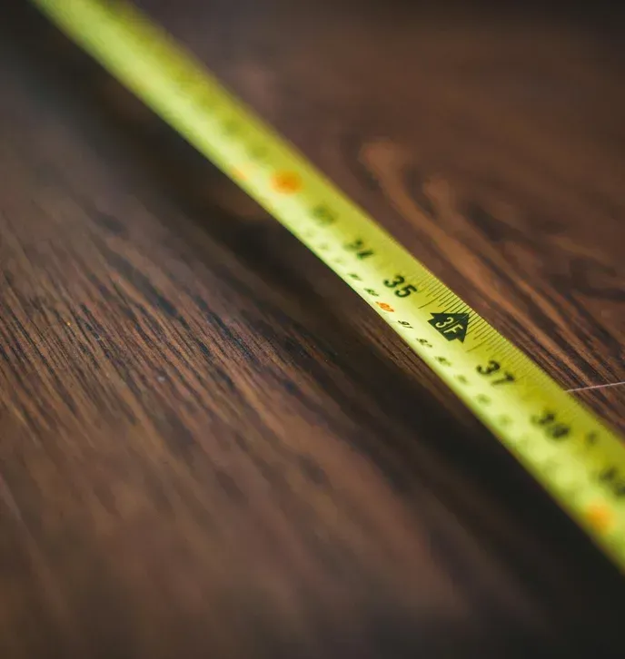 Yellow tape measure on a dark wood surface, with numbers visible from 34 to 39 inches.