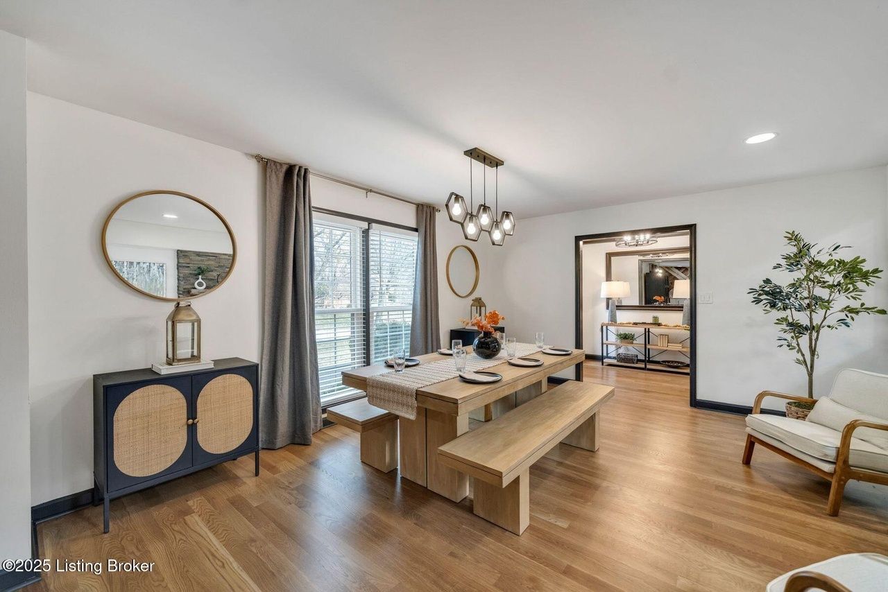 Spacious dining room with wooden table, benches, and a side cabinet. Neutral tones with a view through a sliding door.