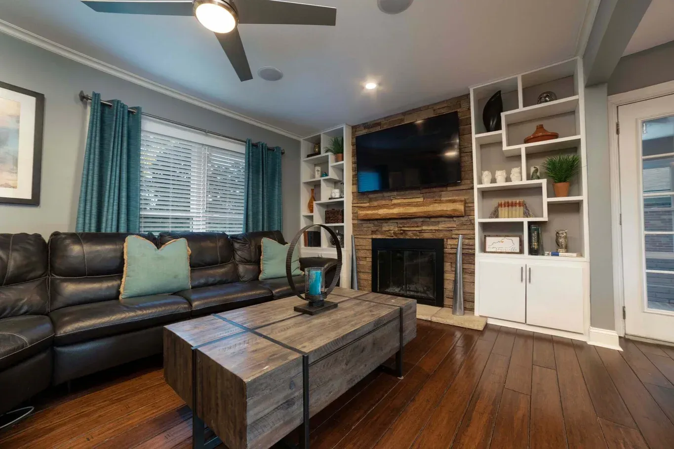 Living room with a leather sofa, teal accents, a fireplace, and built-in shelves.