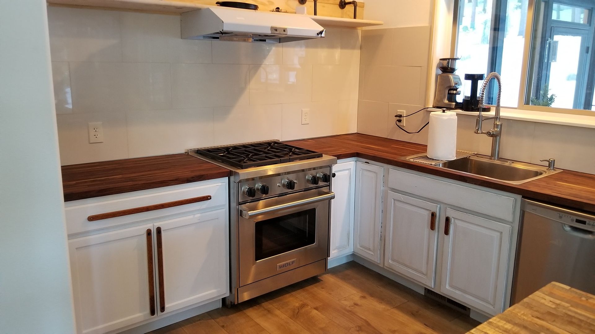 Kitchen with stainless steel range, white cabinets, and butcher block counters.