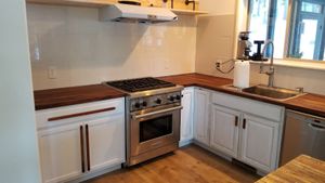 Kitchen with stainless steel range, white cabinets, and butcher block counters.