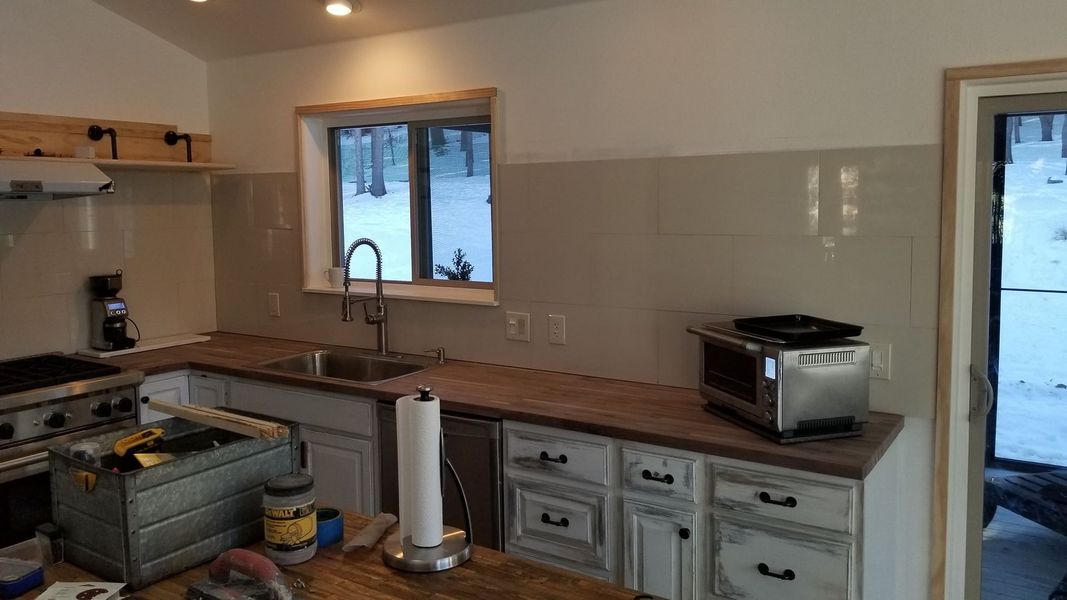 Kitchen with white cabinets, wood countertops, and stainless steel sink and appliances.