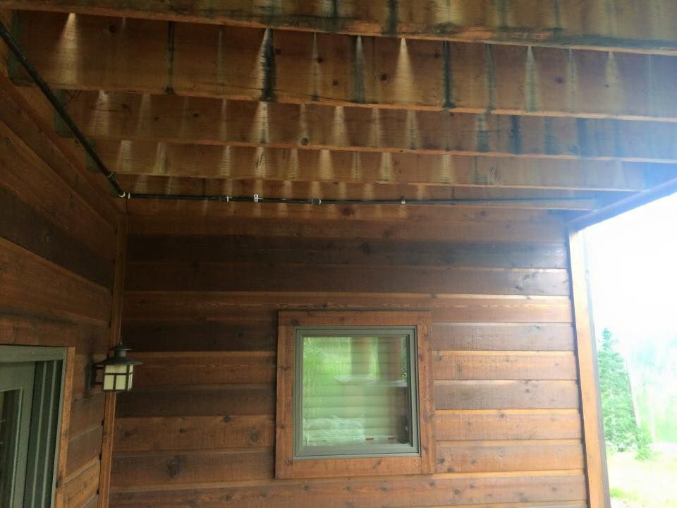 Wooden building exterior with a shaded porch ceiling and a small window.
