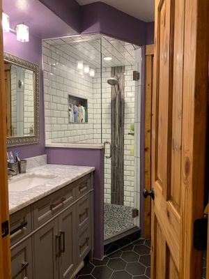 Bathroom with gray vanity, white subway tile shower, purple walls, and wood trim.