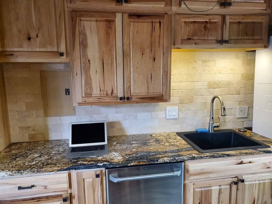 Kitchen with natural wood cabinets, granite countertops, stone backsplash, and stainless steel sink and appliances.