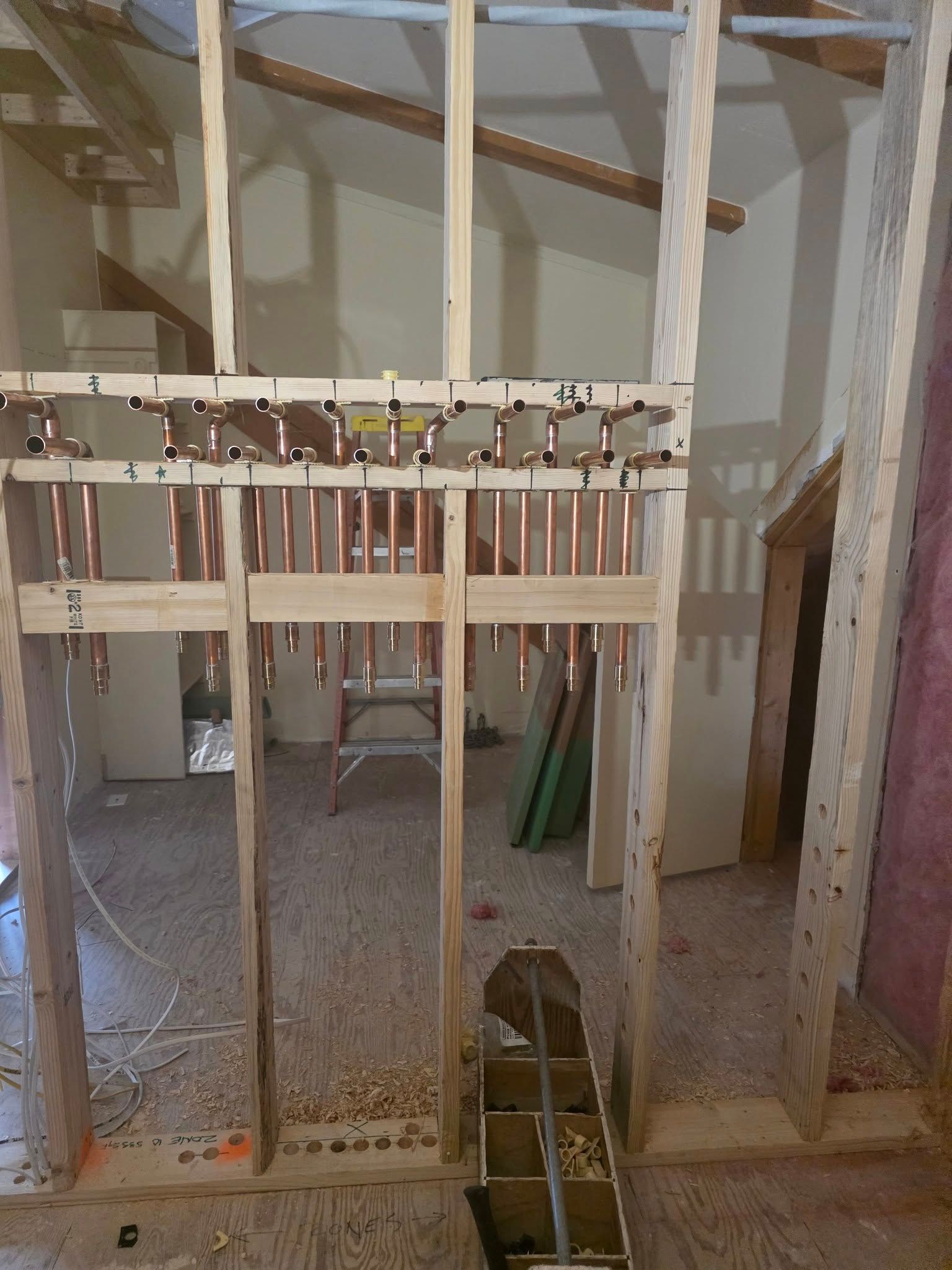 Copper plumbing pipes installed in a wooden wall frame during construction.