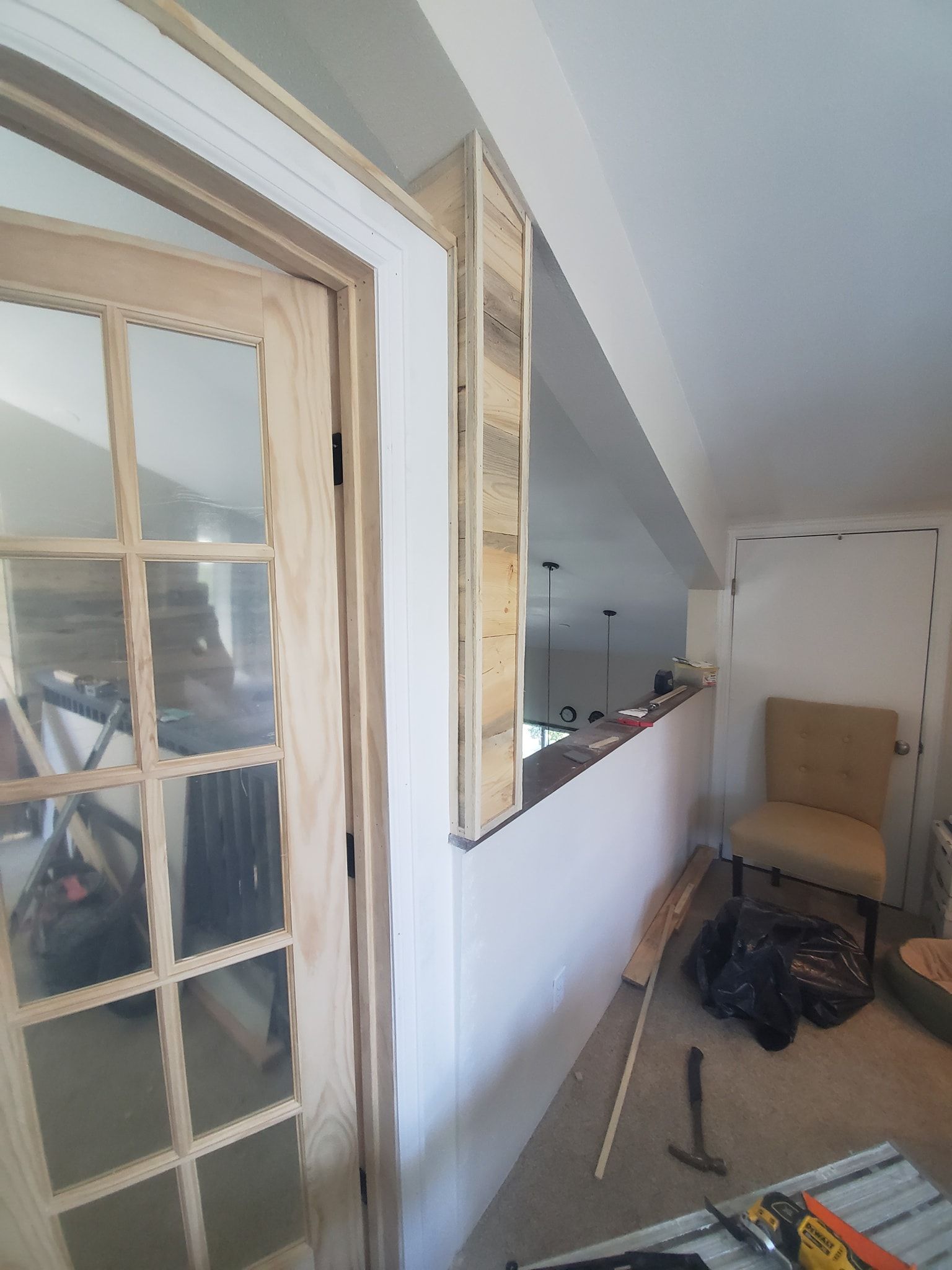 Interior renovation with wooden door, paneling, and a half wall. Carpentry tools are visible.