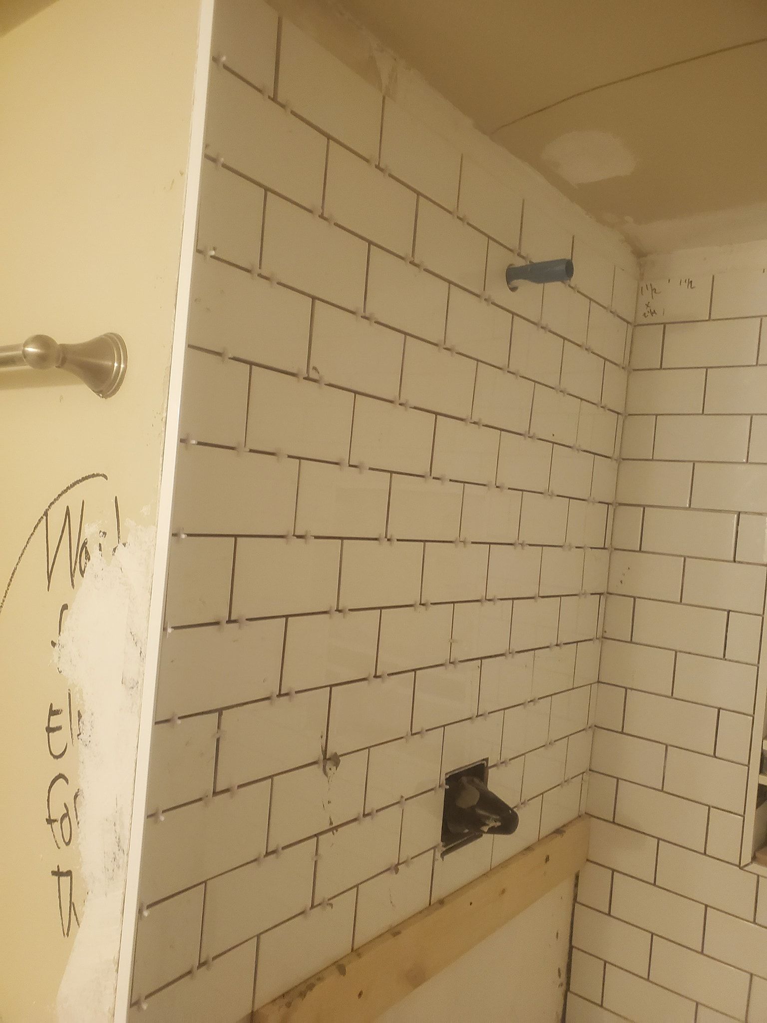 White subway tile bathroom wall in progress with fixtures.