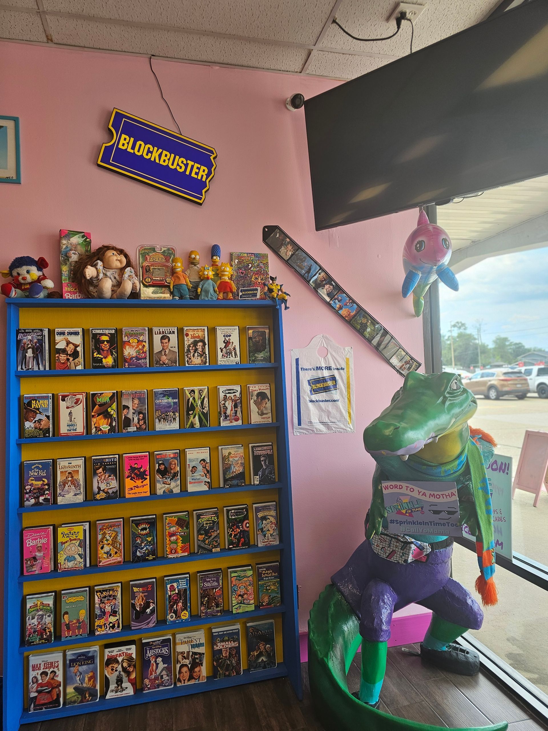 A display of vhs tapes in a store with a statue of a crocodile