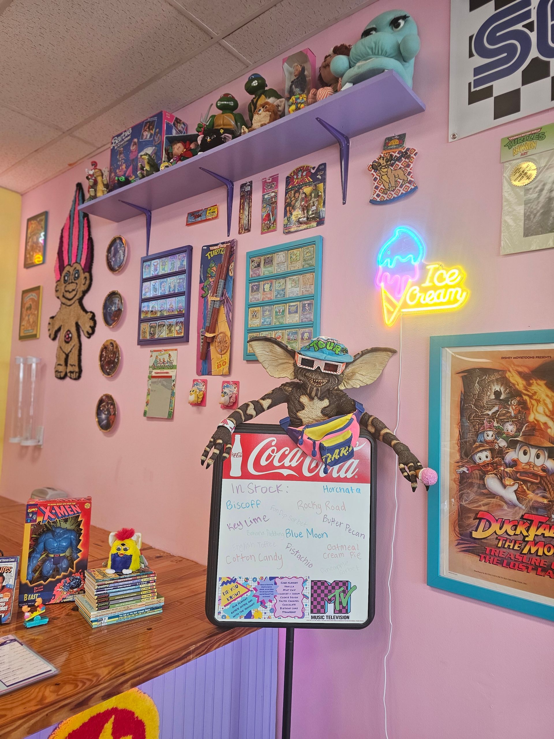 A gremlin is sitting on a sign that says coca cola