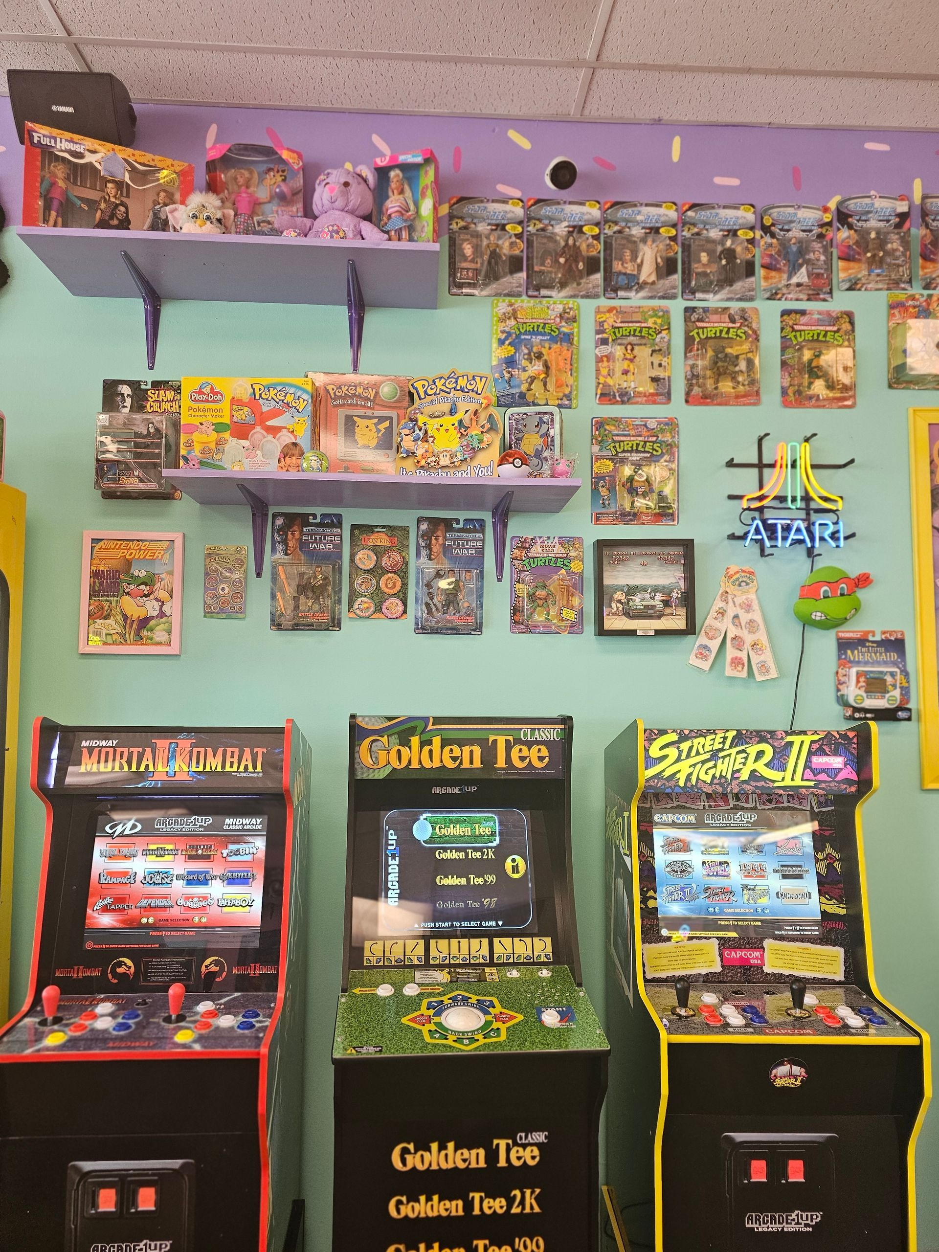 Three arcade machines with one that says golden tee on it