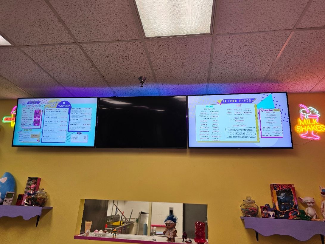 A restaurant with two televisions and a neon sign on the wall.