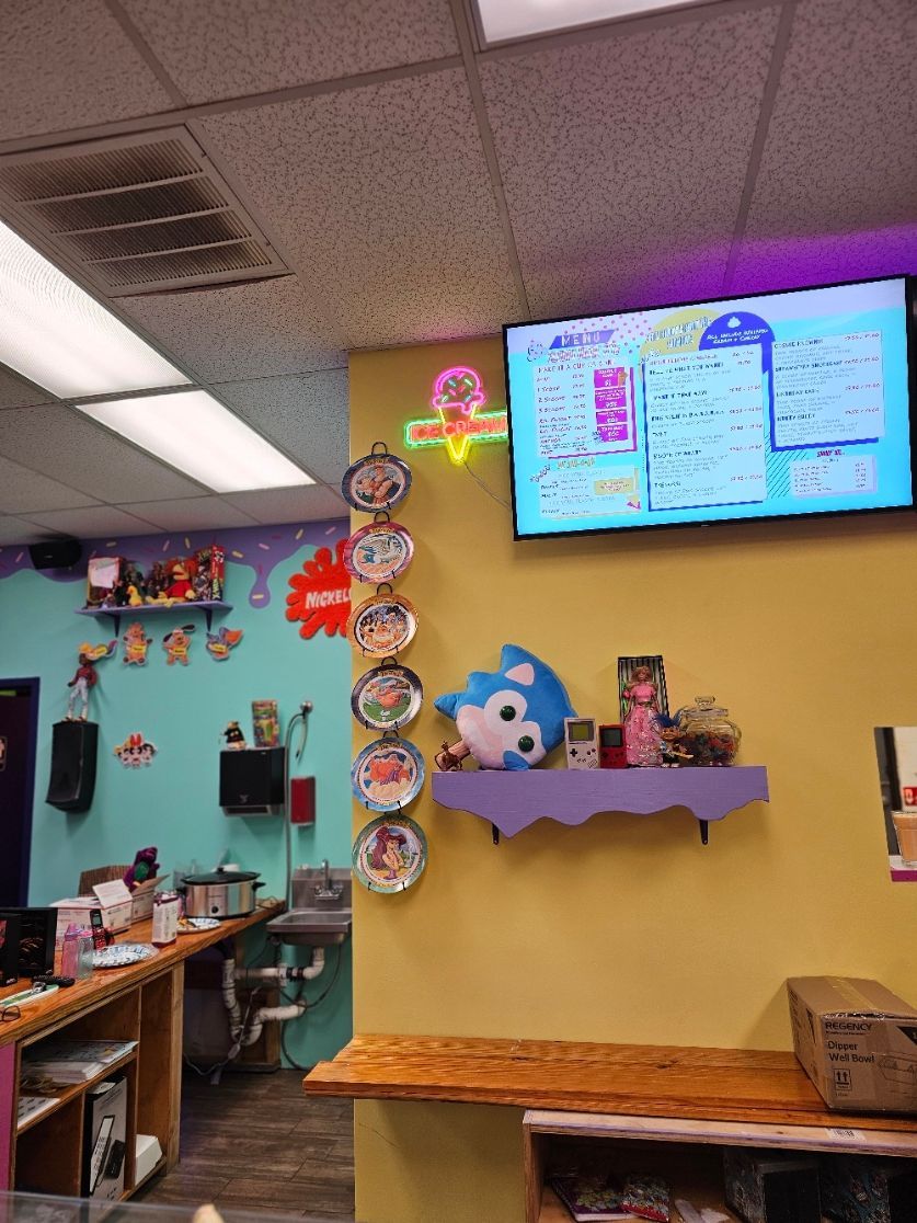 A restaurant with a large tv on the wall above the counter