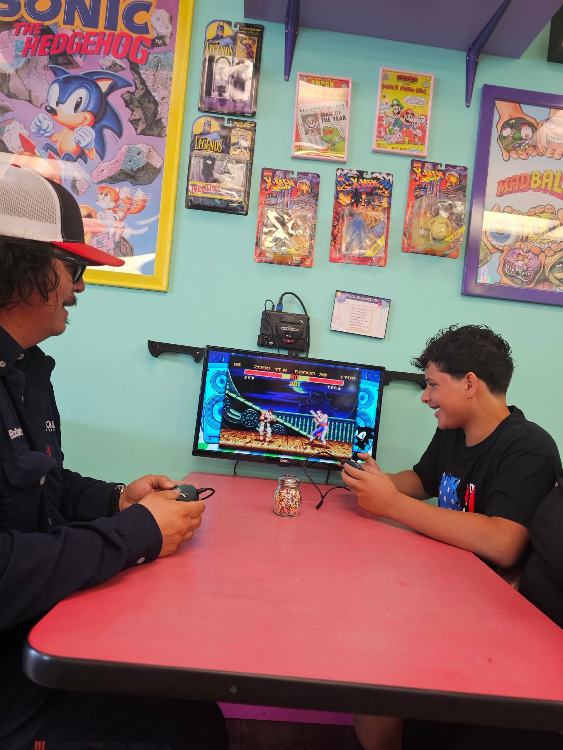 Two boys are playing a video game in front of a sonic the hedgehog poster