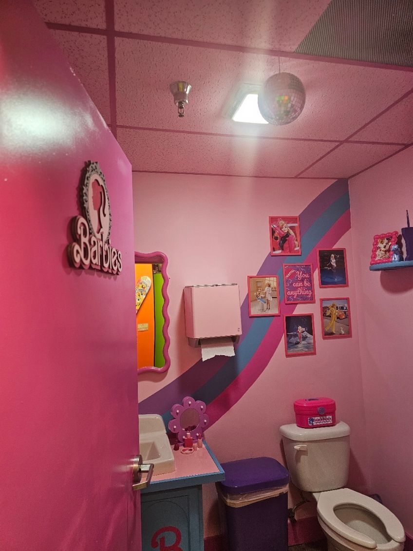 A pink bathroom with a toilet a sink and a mirror