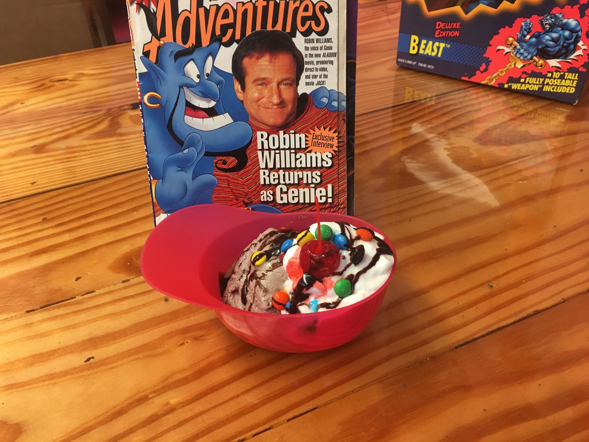 A bowl of ice cream next to a box of robin williams adventures