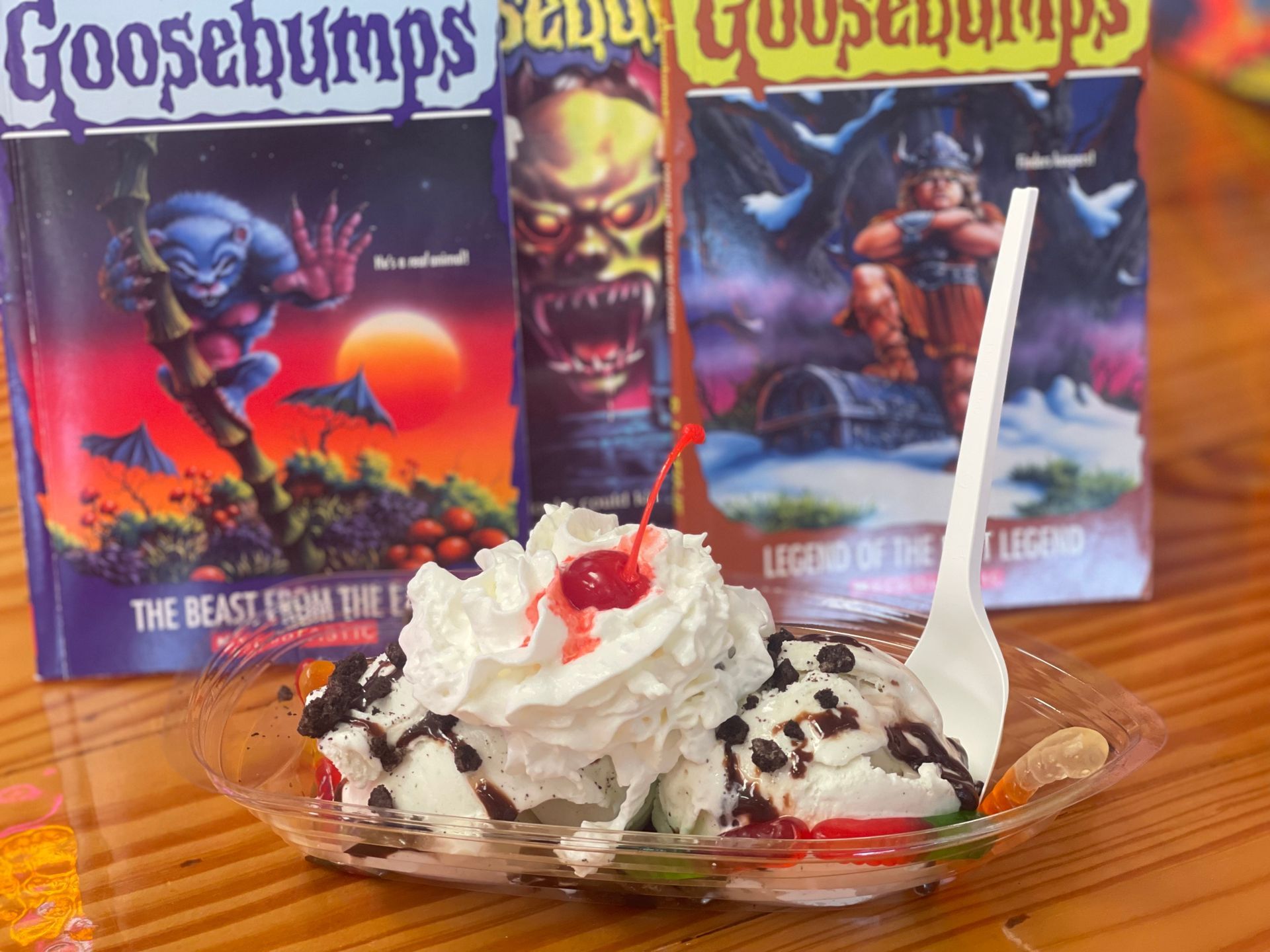 A bowl of ice cream with whipped cream and a cherry in front of two goosebumps books.