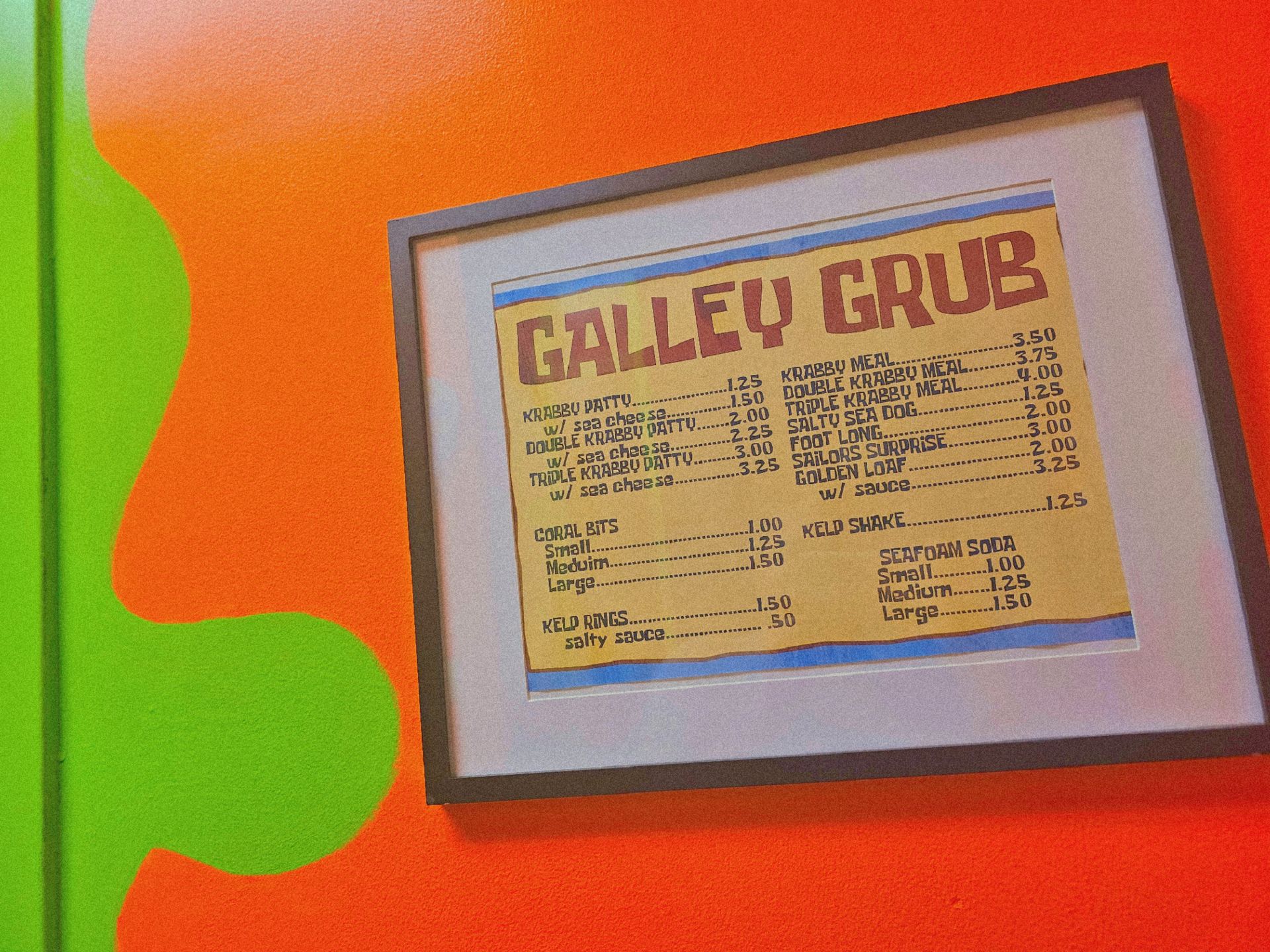 A framed menu for galley grub hangs on a wall