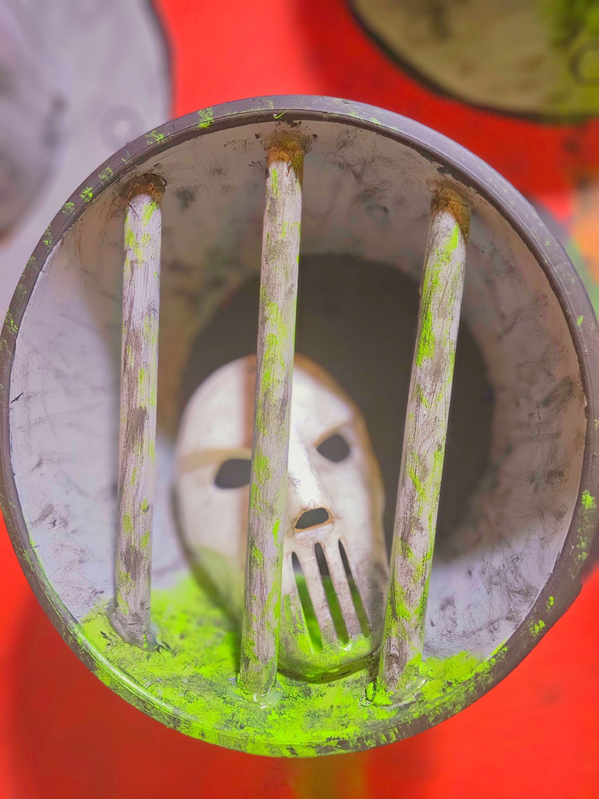 A mask is behind bars in a trash can.
