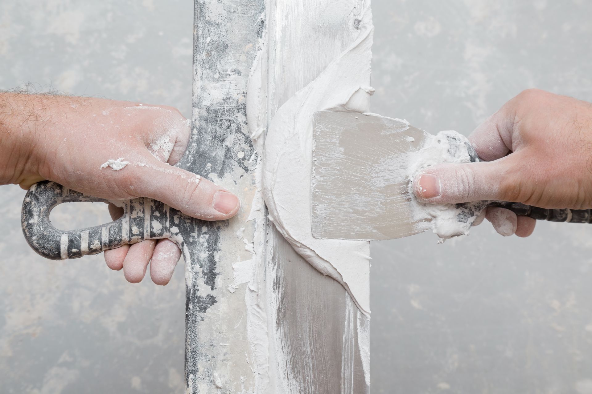 A man is plastering a wall with a spatula.