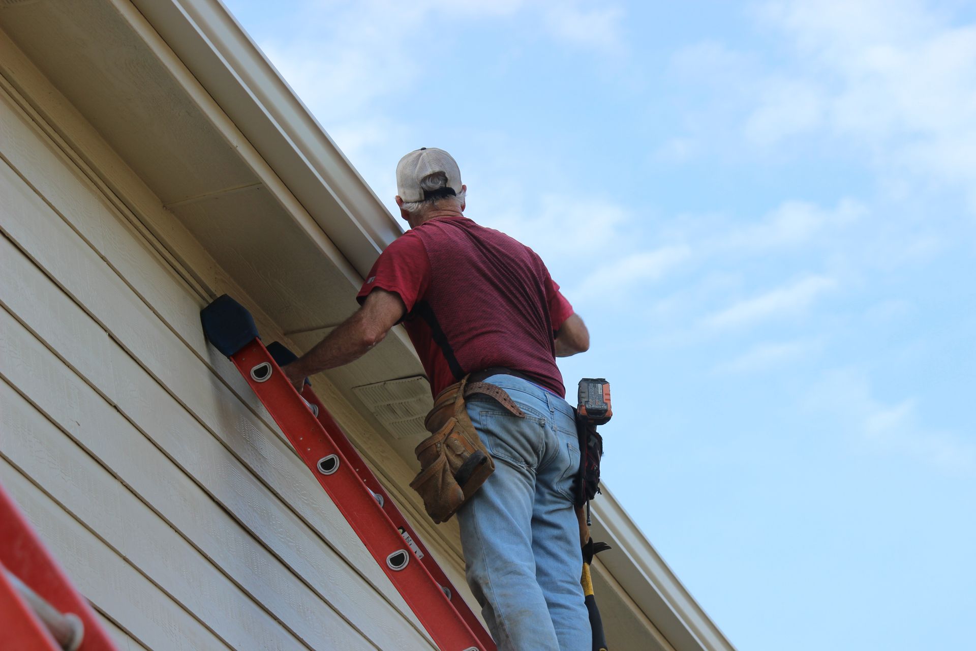 A man is standing on a ladder on the side of a building.
