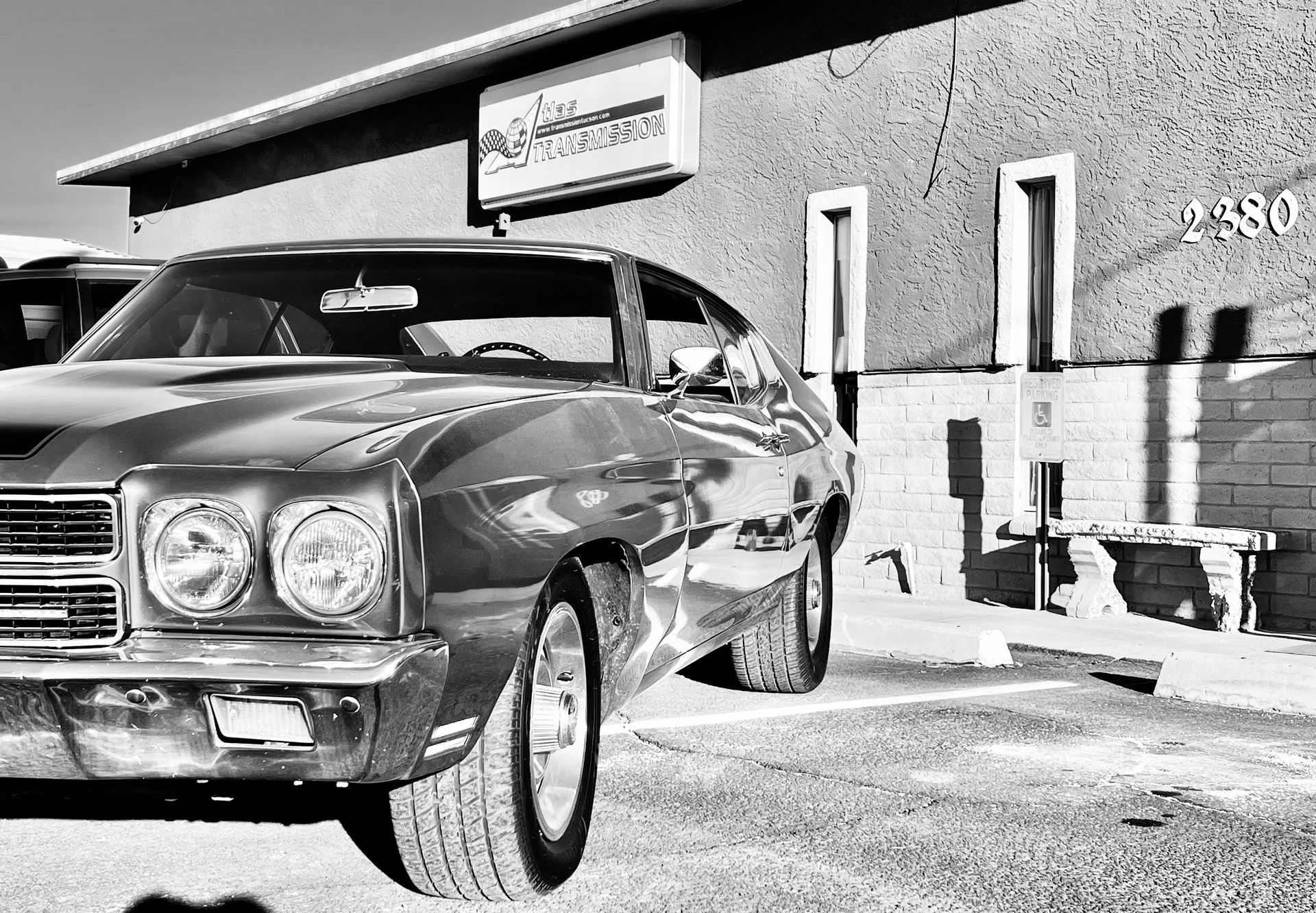A black and white photo of a car parked in front of a building